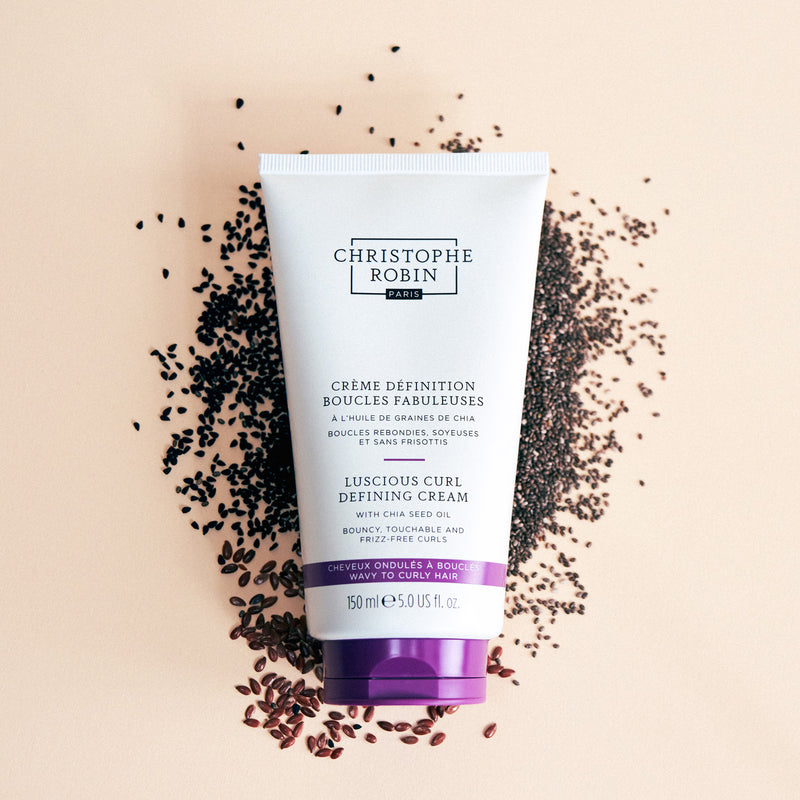 Tube of Christophe Robin Luscious Curl Defining Cream on a beige background with black seeds.