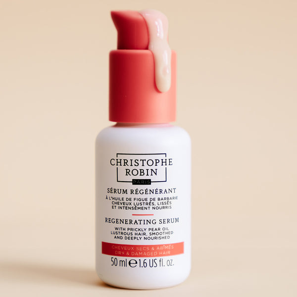 Christophe Robin Regenerating serum bottle with red cap showing serum texture on a beige background