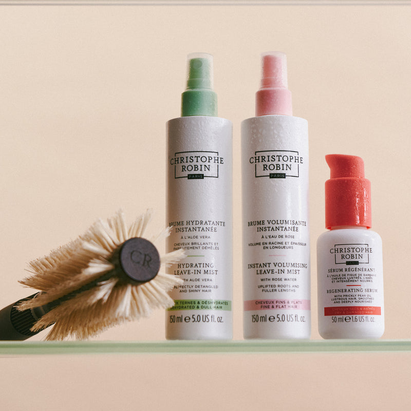 Christophe Robin hydrating and volumising mists and regenerating serum on a beige background with a brush.