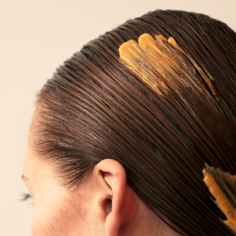 Person with hair being treated with Christophe Robin shade variation mask in chic copper applied on wet hair 