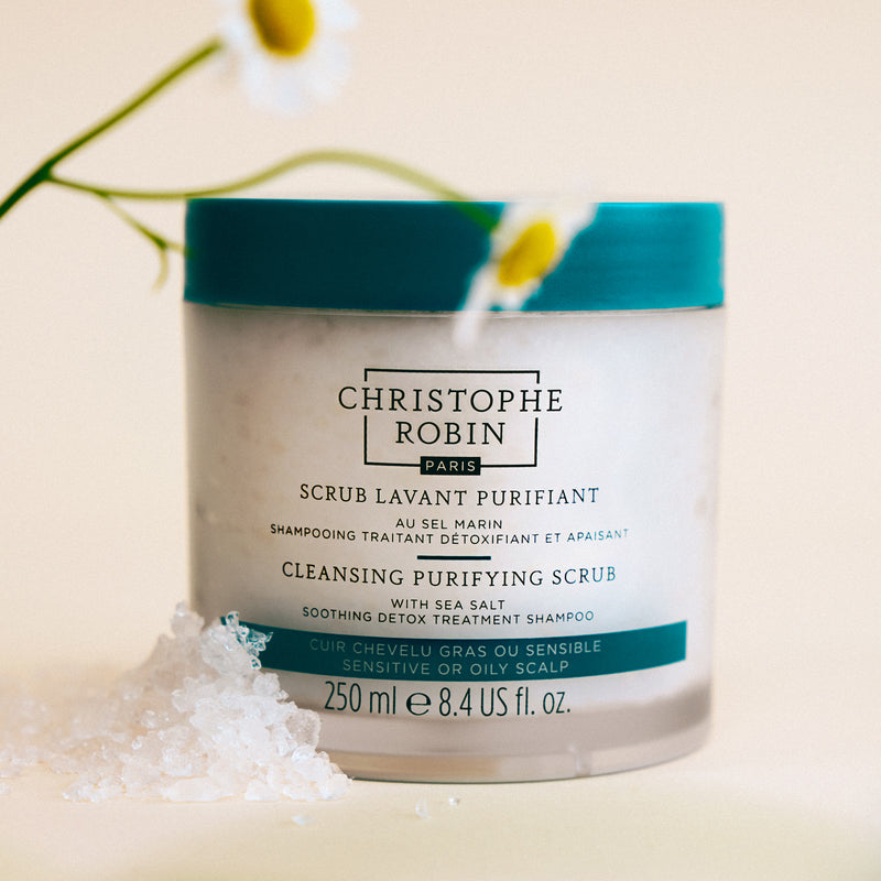 Cleansing purifying scrub container with brand name and ingredients on a light background