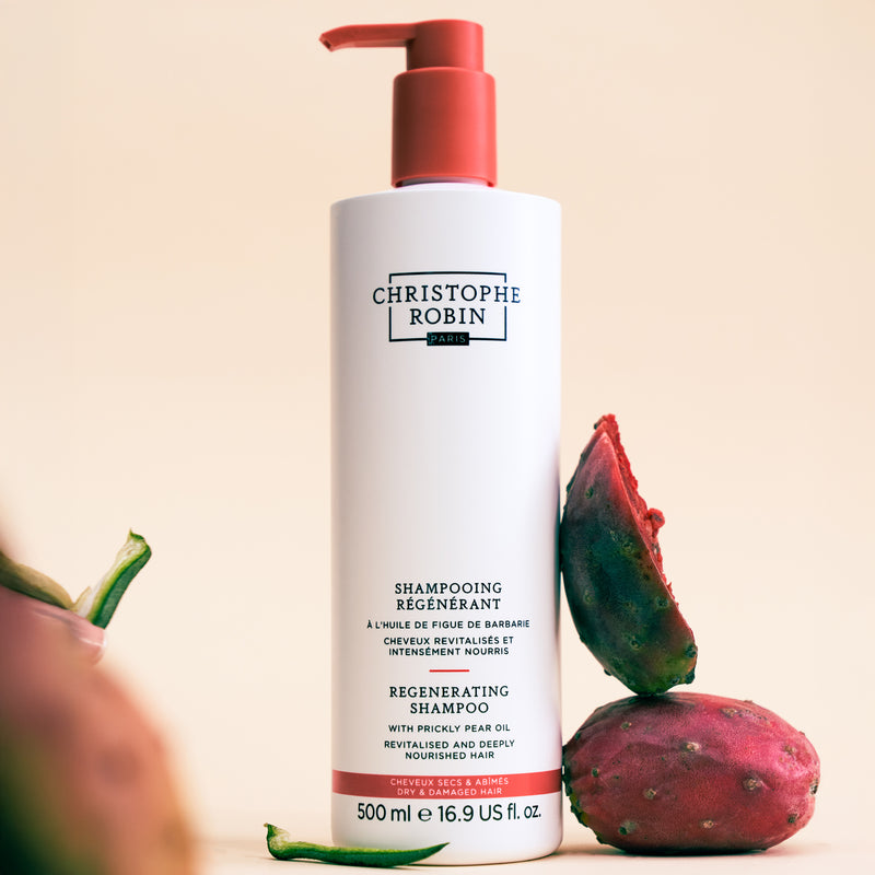 Christophe Robin Regenerating shampoo bottle 500ml sized with a red pump on a beige background, featuring a prickly pear fruit