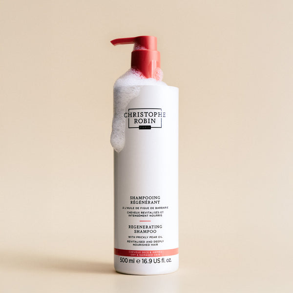 Bottle of Christophe Robin shampoo 500ml with pump on a beige background