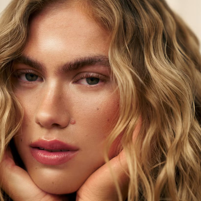 Close-up of a person with blonde hair and pink lipstick.