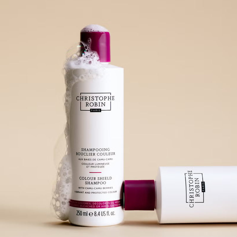 Christophe Robin colour shield shampoo bottle with foamy head on beige background