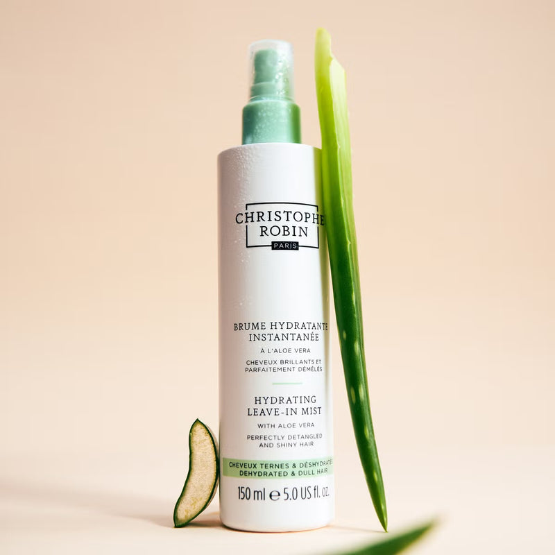 Christophe Robin hydrating leave-in mist bottle with aloe vera leaves on a beige background