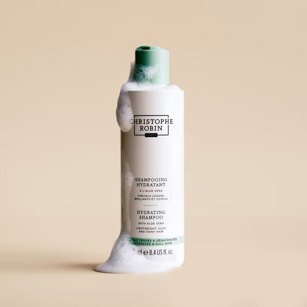 Christophe Robin hydrating shampoo bottle with green cap on a beige background