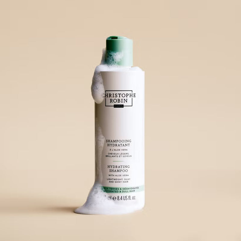 Christophe Robin hydrating shampoo bottle with green cap on a beige background