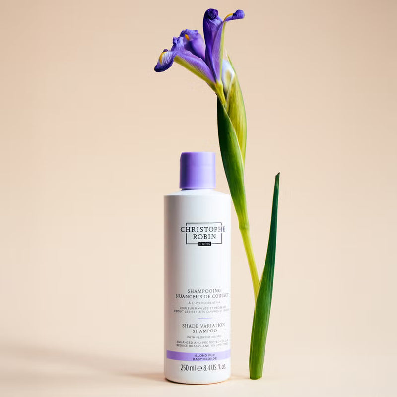 Bottle of Christophe Robin blonde shampoo with a purple flower on a beige background