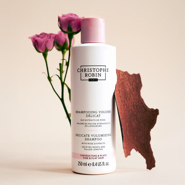 Christophe Robin Volumising shampoo bottle with pink roses on a beige background